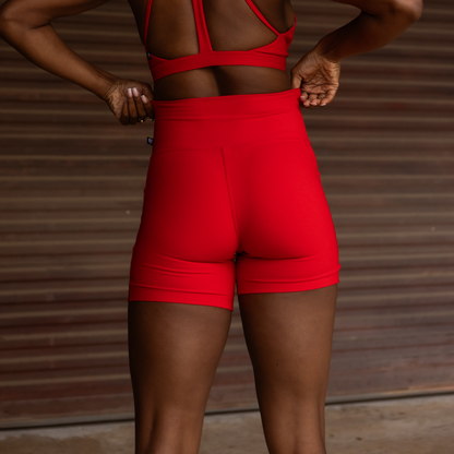 Person wearing red athletic shorts against a wooden background