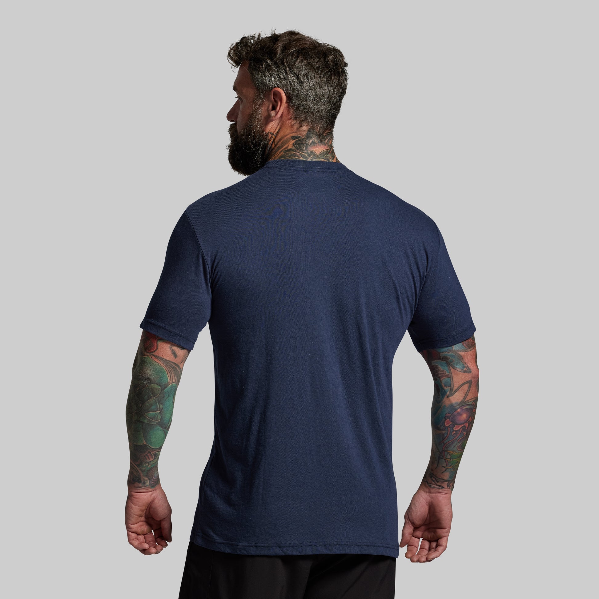 Man wearing a navy blue t-shirt on a gray background