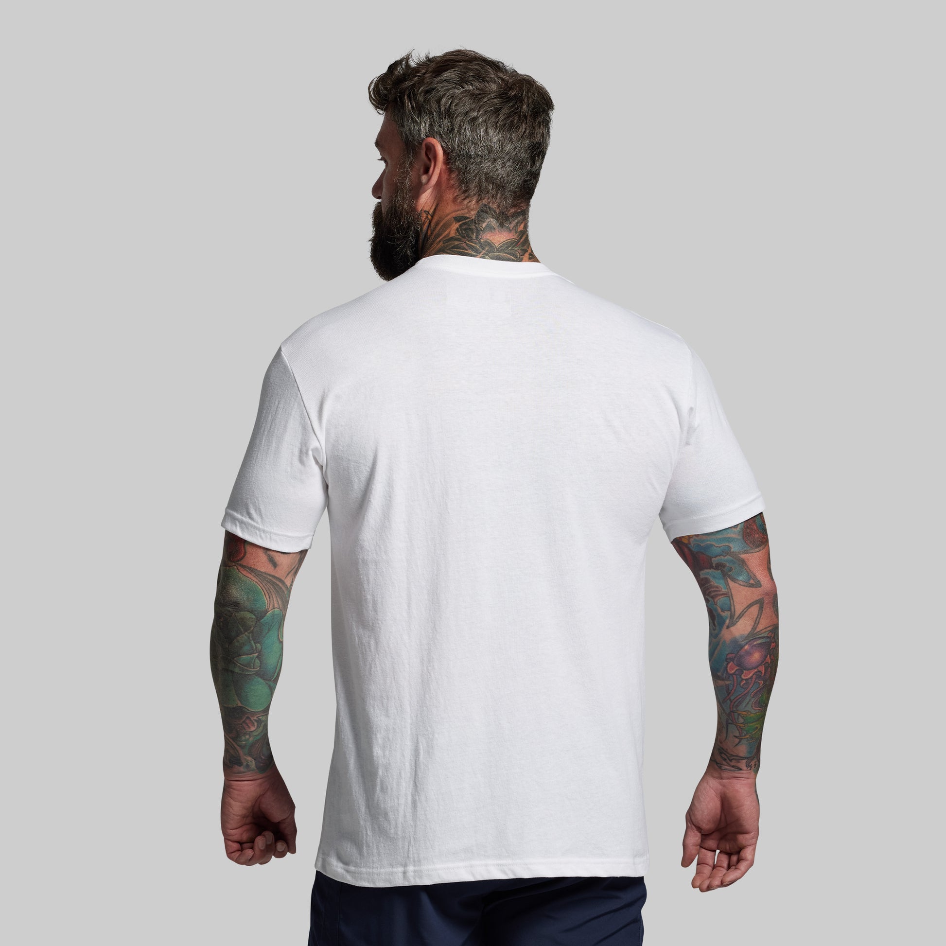 Man wearing a plain white t-shirt against a gray background