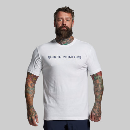Man wearing a white 'Born Primitive' t-shirt against a gray background