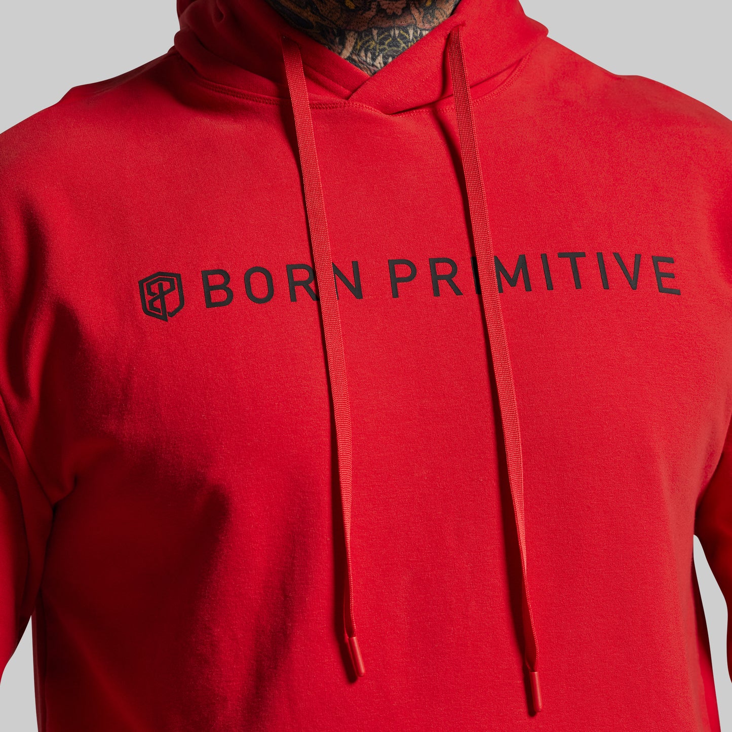 Red hoodie with 'Born Primitive' logo on a gray background