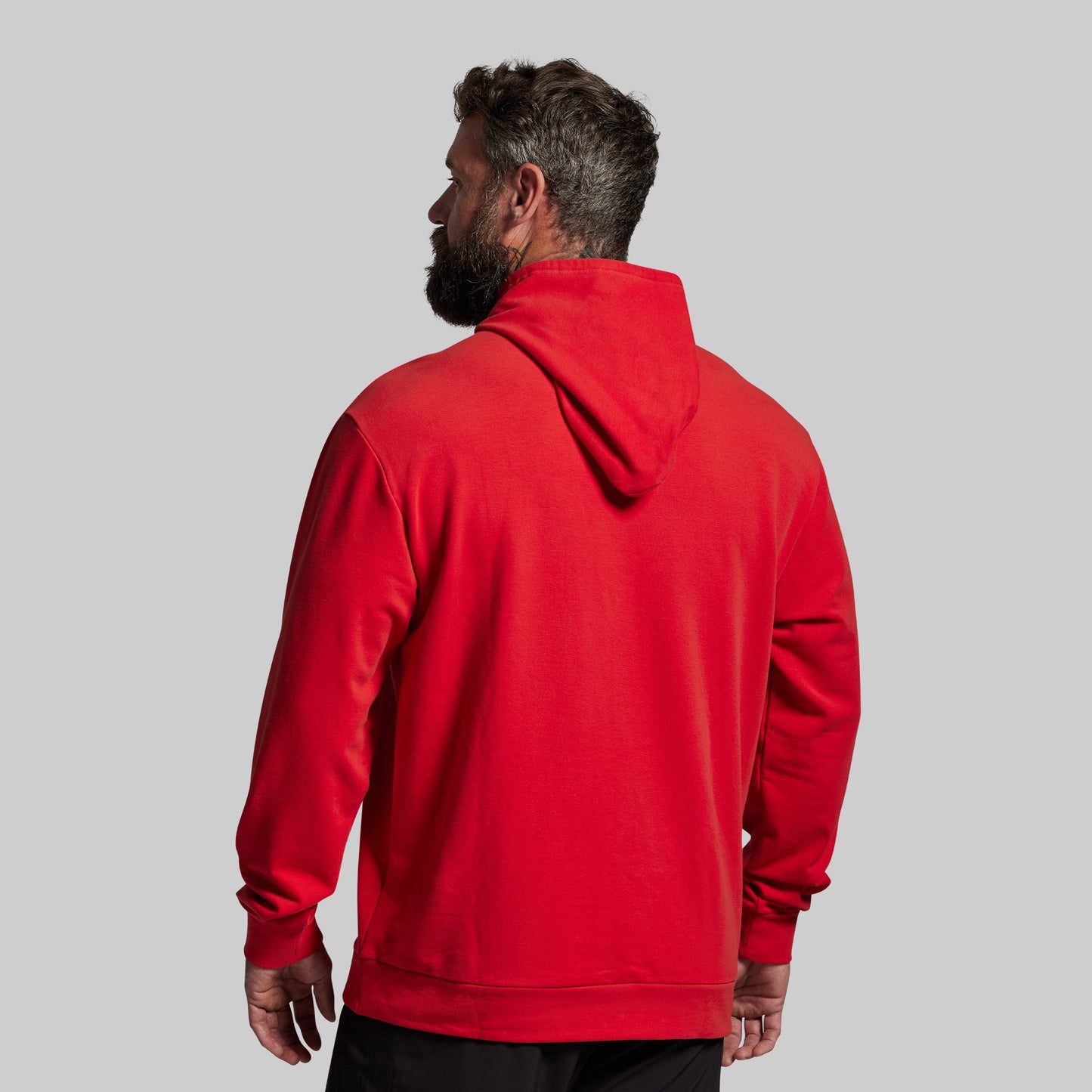 Man wearing a red hoodie from behind on a gray background