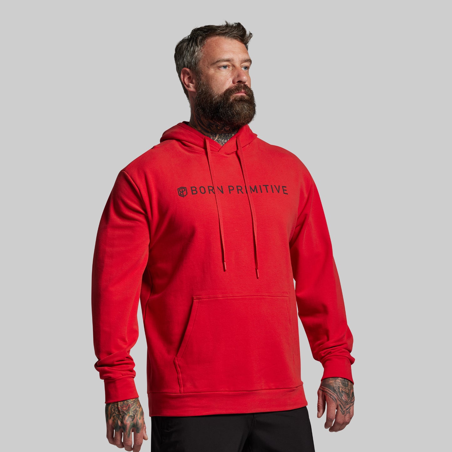 Man wearing a red hoodie with 'BORN PRIMITIVE' logo on a gray background