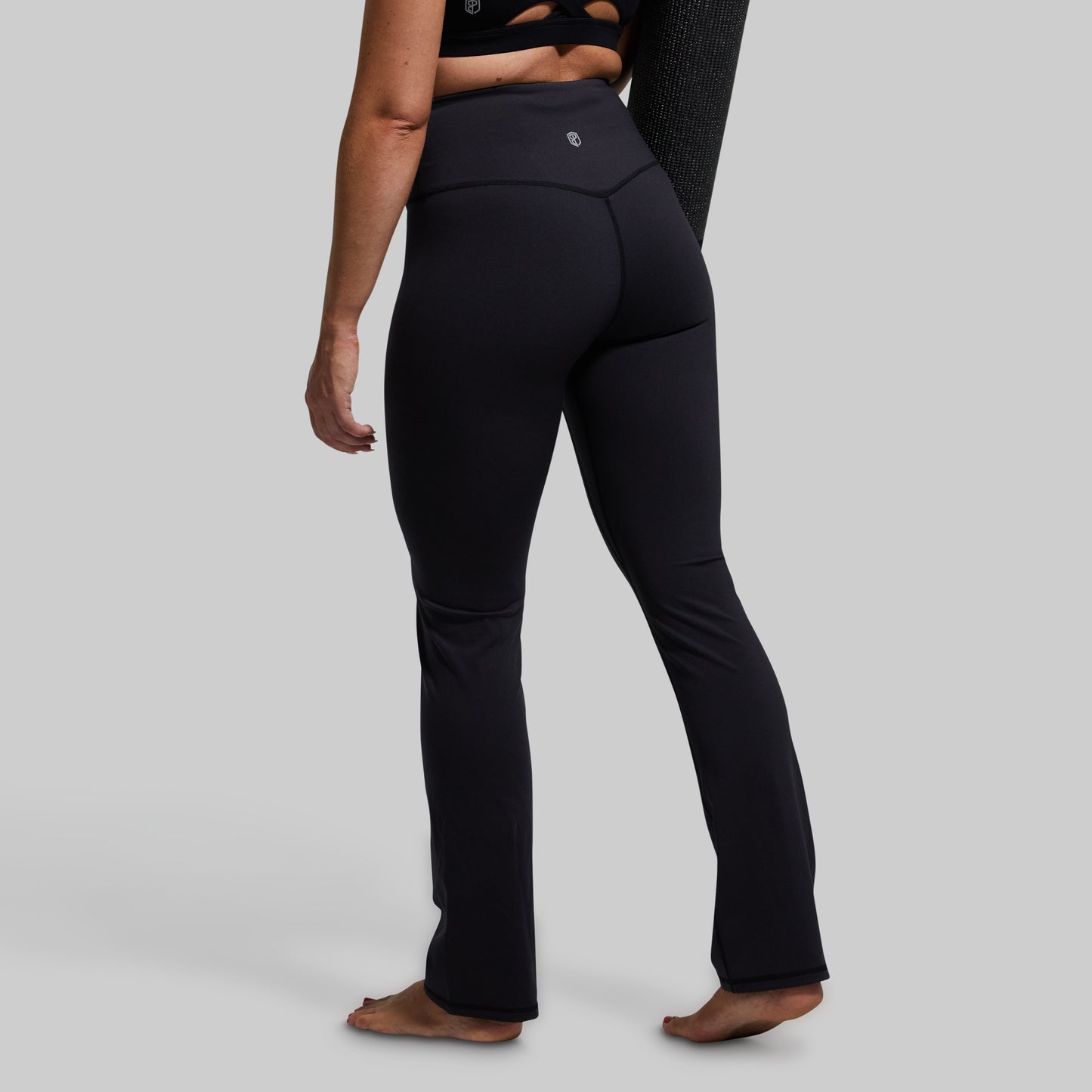 Person wearing black yoga pants on a plain background