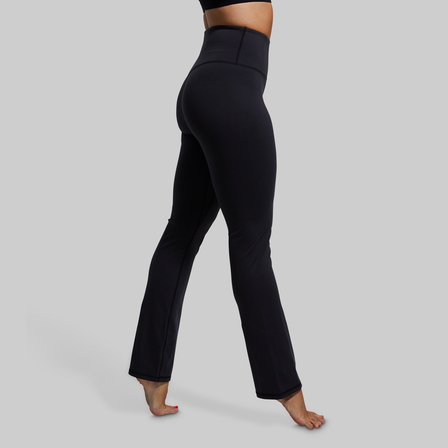 Black yoga pants worn by a person on a gray background