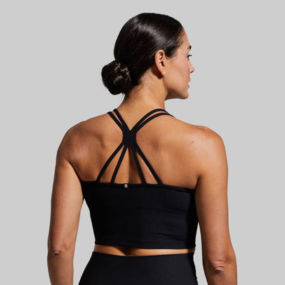 Woman wearing a black sports bra and leggings on a gray background