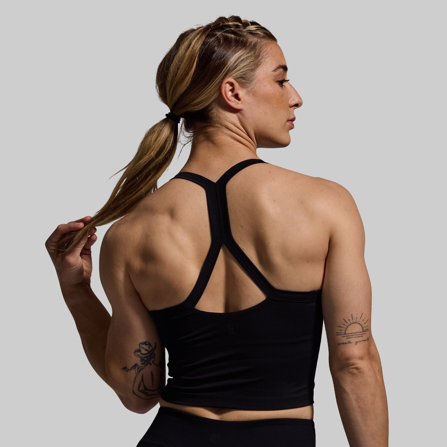 Woman wearing a black sports bra with a gray background