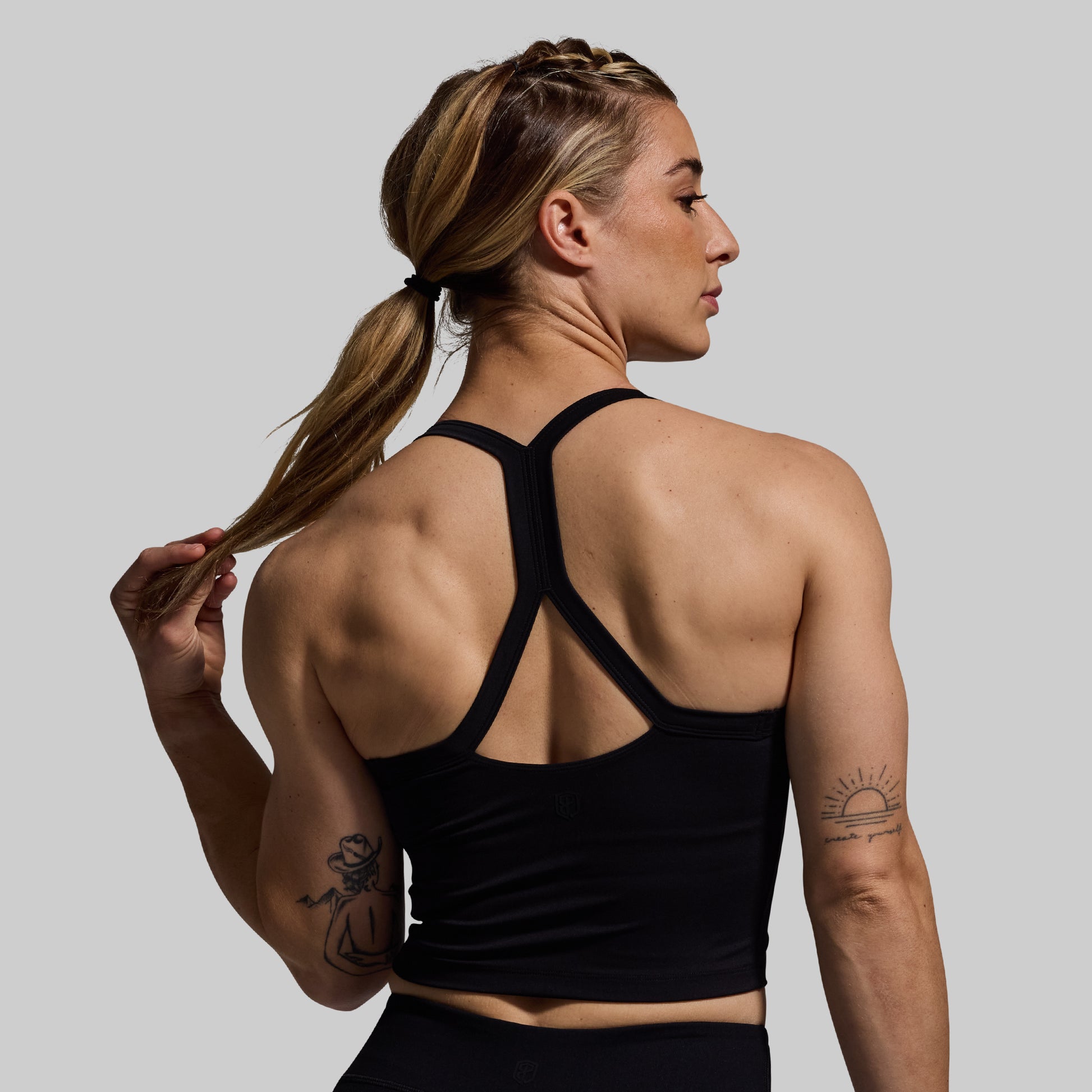 Woman wearing a black sports bra with a gray background