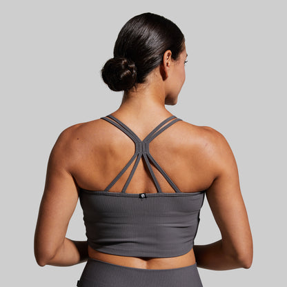 Woman wearing a gray sports bra and leggings on a gray background