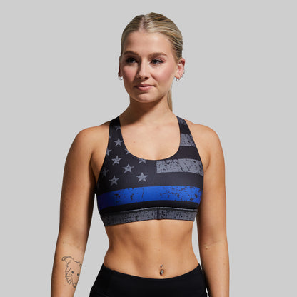 Woman wearing a sports bra with a blue stripe design on a gray background