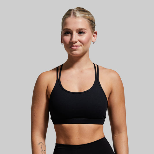 Woman wearing a black sports bra against a plain background