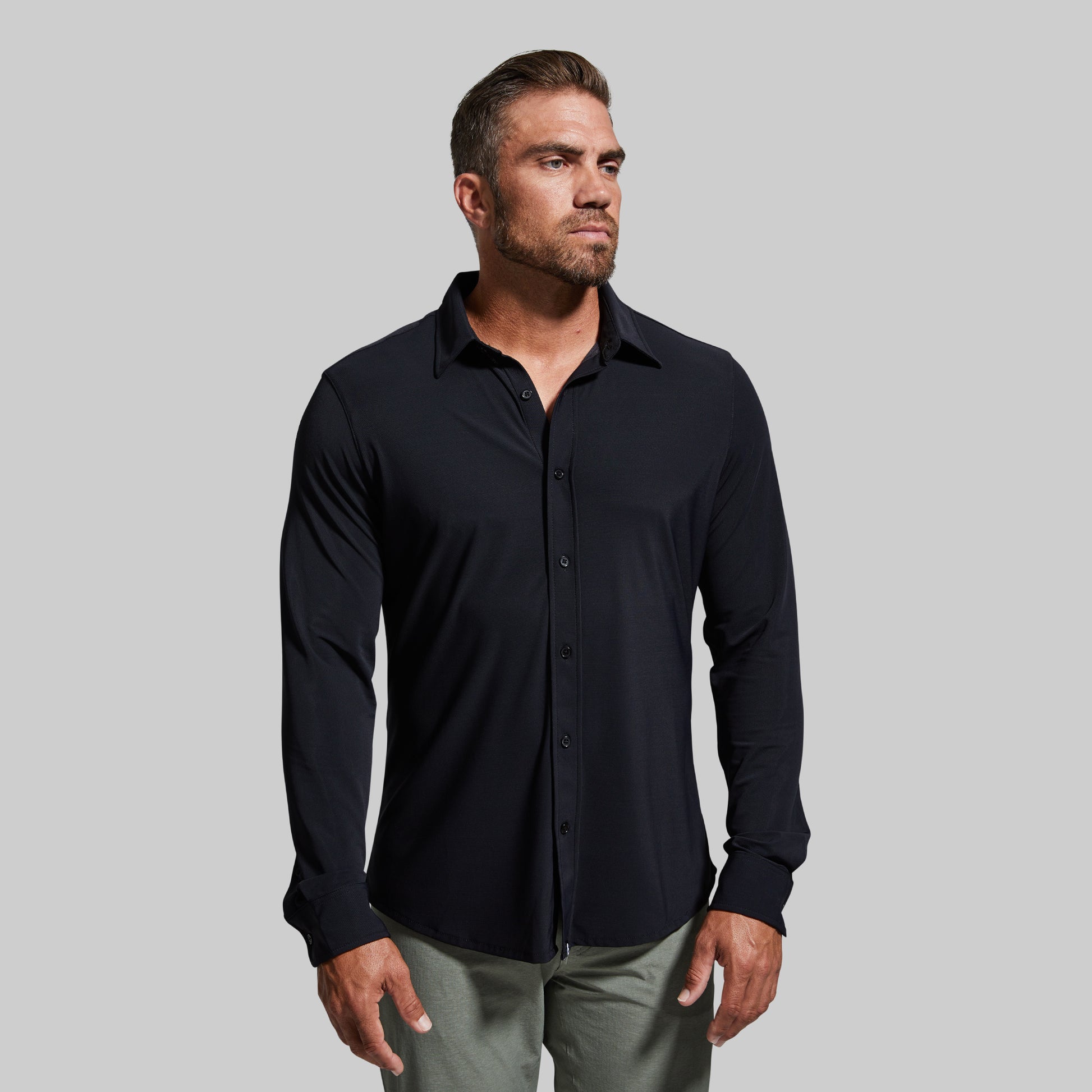Man wearing a black button-up shirt against a gray background