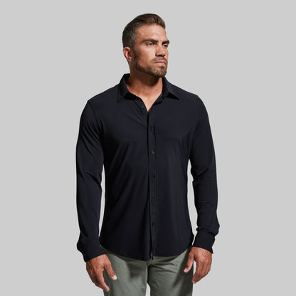Man wearing a black button-up shirt against a gray background