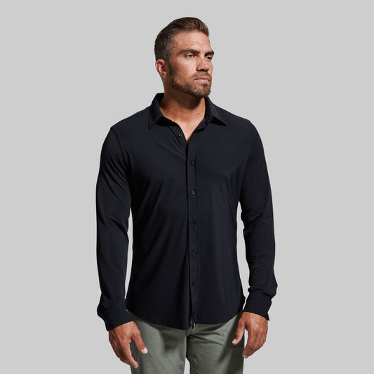 Man wearing a black button-up shirt against a gray background