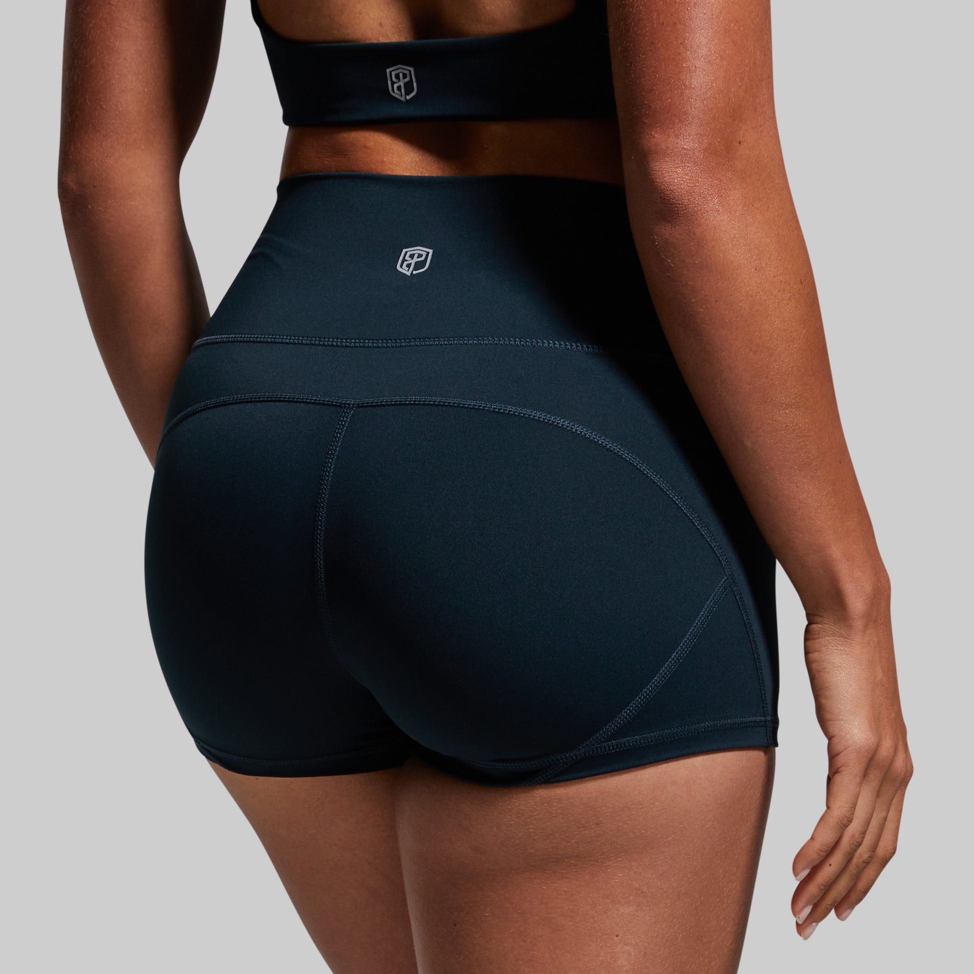 Person wearing dark green athletic shorts on a plain background