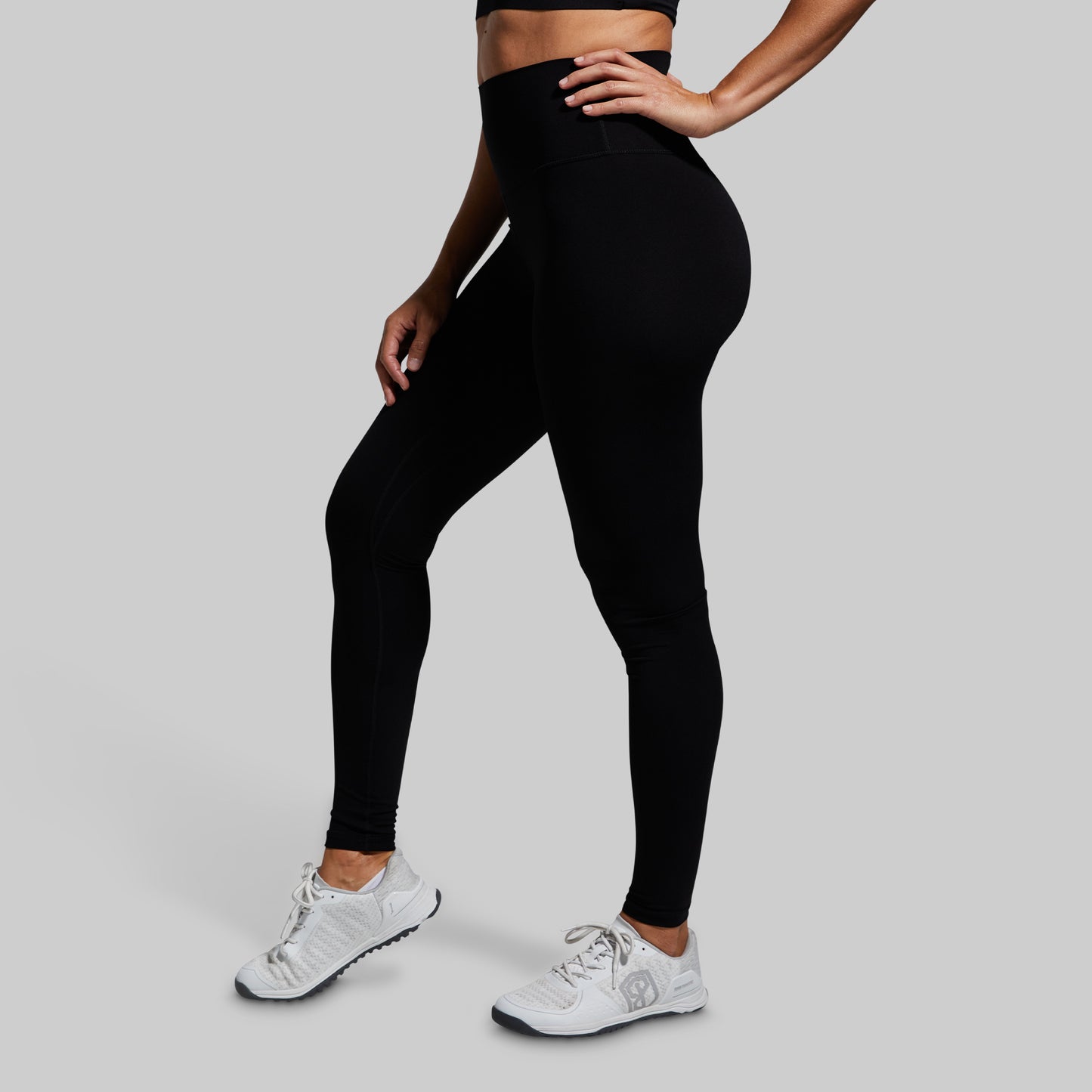 Person wearing black leggings and white sneakers on a gray background