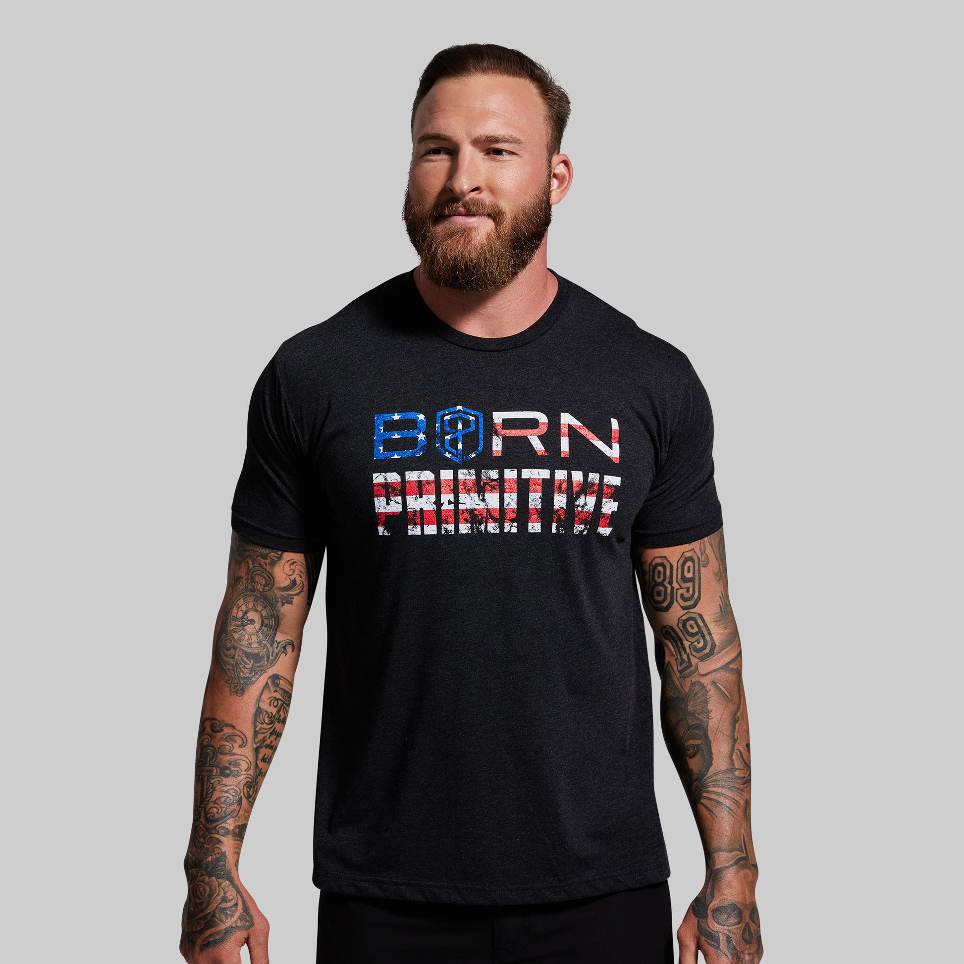 Man wearing a black t-shirt with 'Born Primitive' text on a gray background
