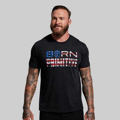 Man wearing a black t-shirt with 'Born Primitive' text on a gray background