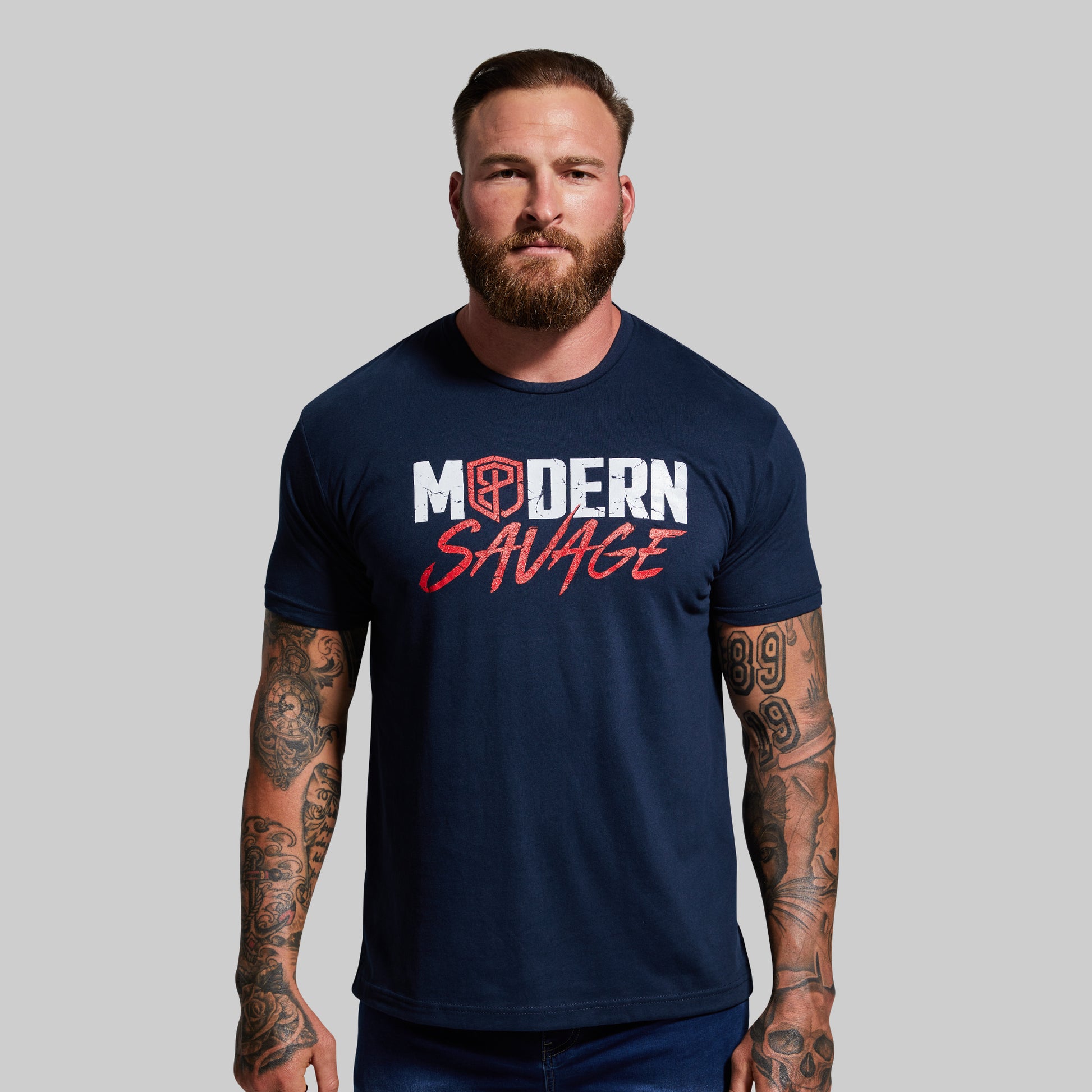 Man wearing a navy blue t-shirt with 'Modern Savage' text on a gray background