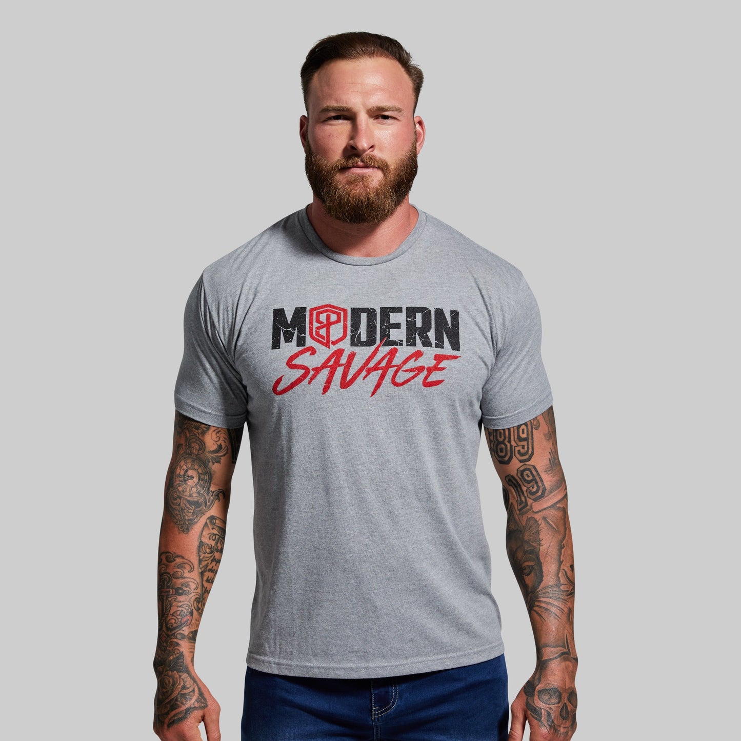 Man wearing a gray t-shirt with 'Modern Savage' logo on a plain background