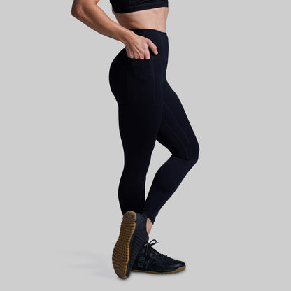 Person wearing black leggings and dark shoes on a light gray background
