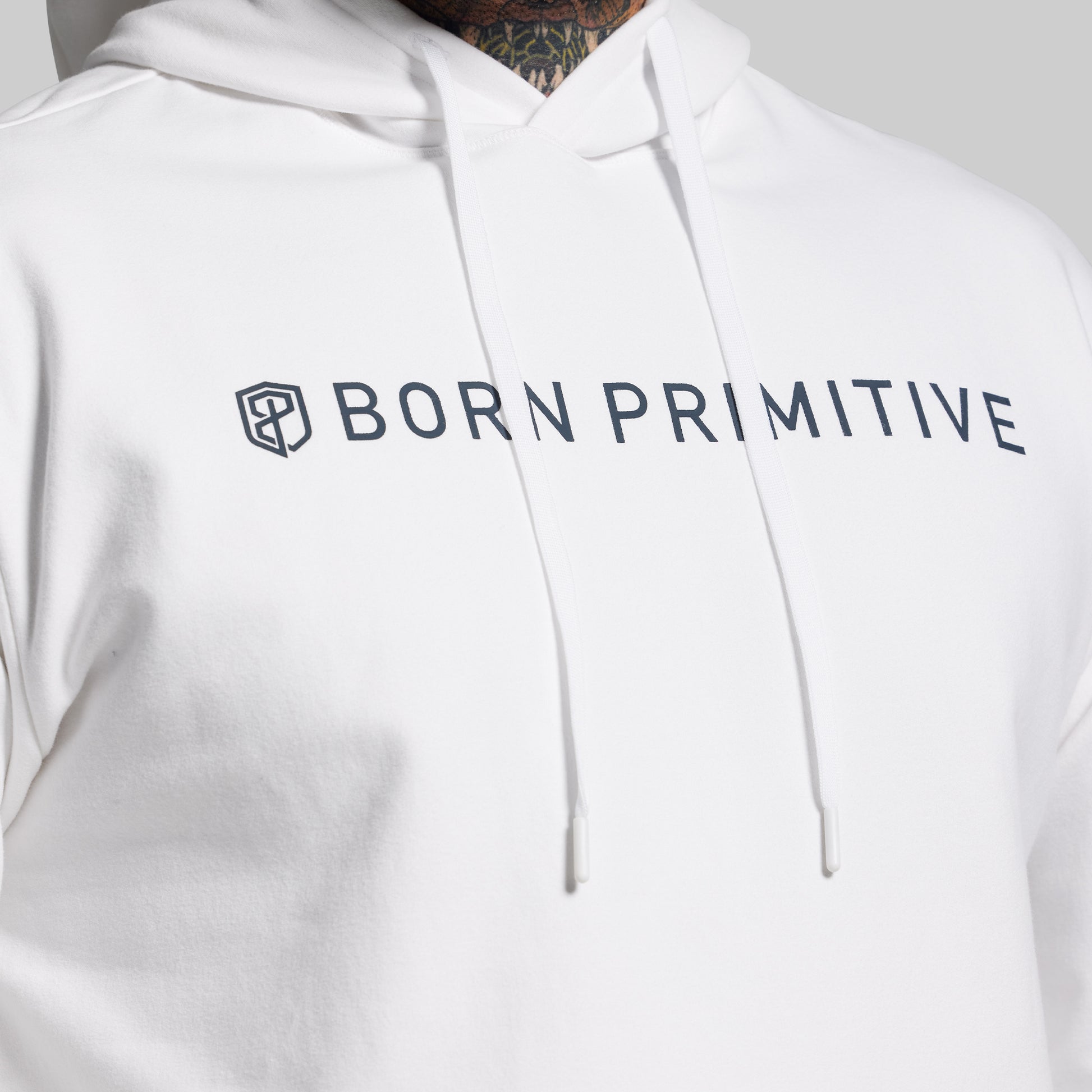 White hoodie with 'Born Primitive' logo on a plain background