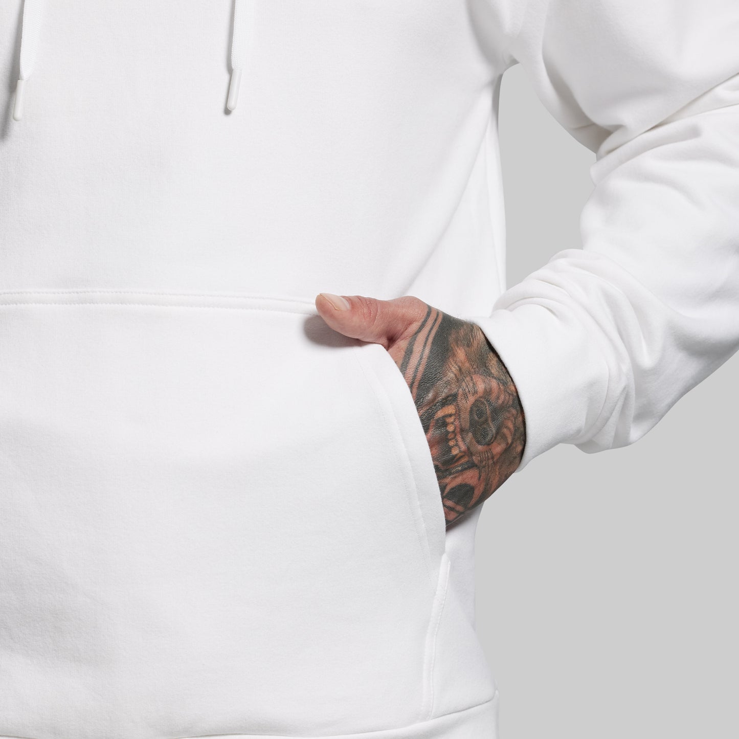 Person wearing a white hoodie with a tattooed arm visible.