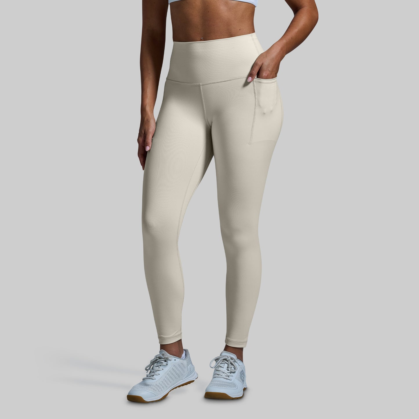 Person wearing beige leggings on a plain background
