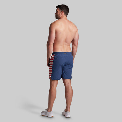 Man wearing blue swim shorts with a colorful pattern on a gray background