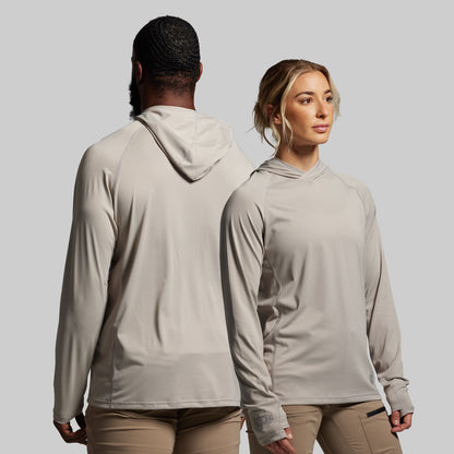 Two people wearing matching beige hoodies and pants against a plain background