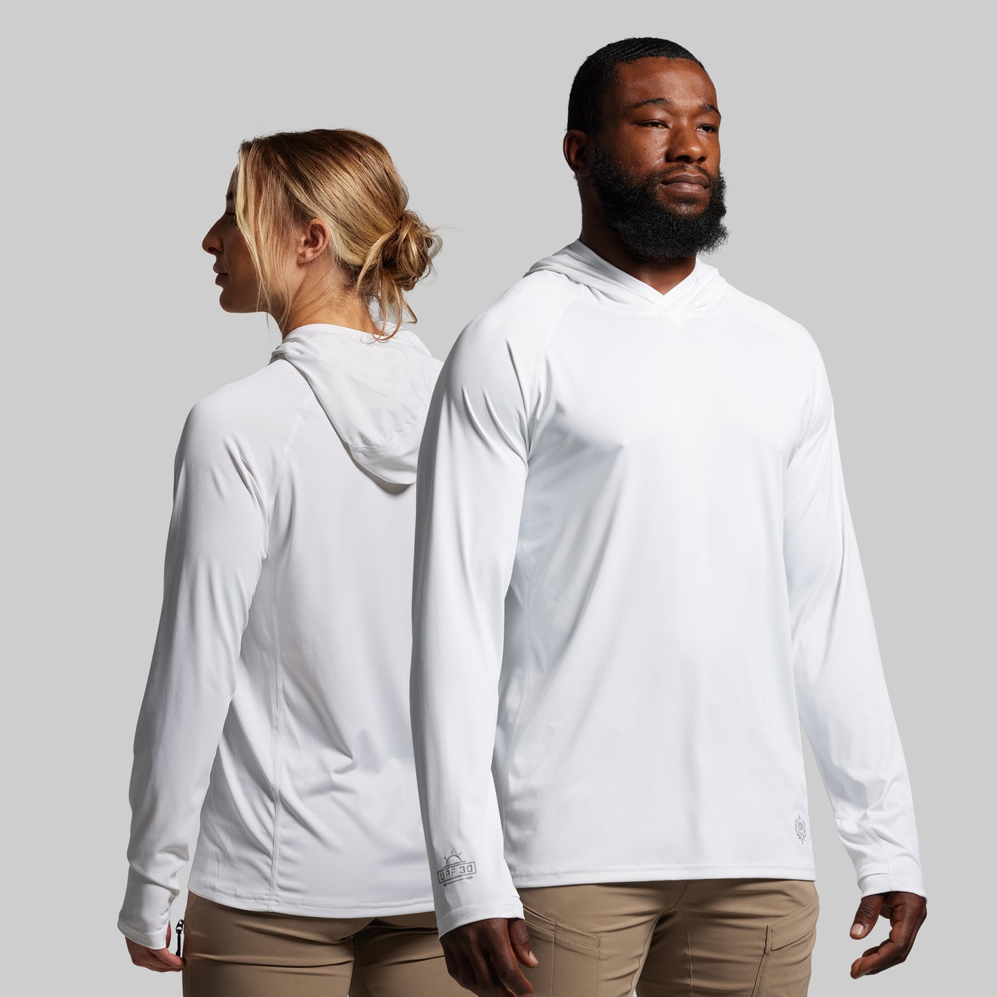 Two people wearing white long-sleeve shirts against a gray background