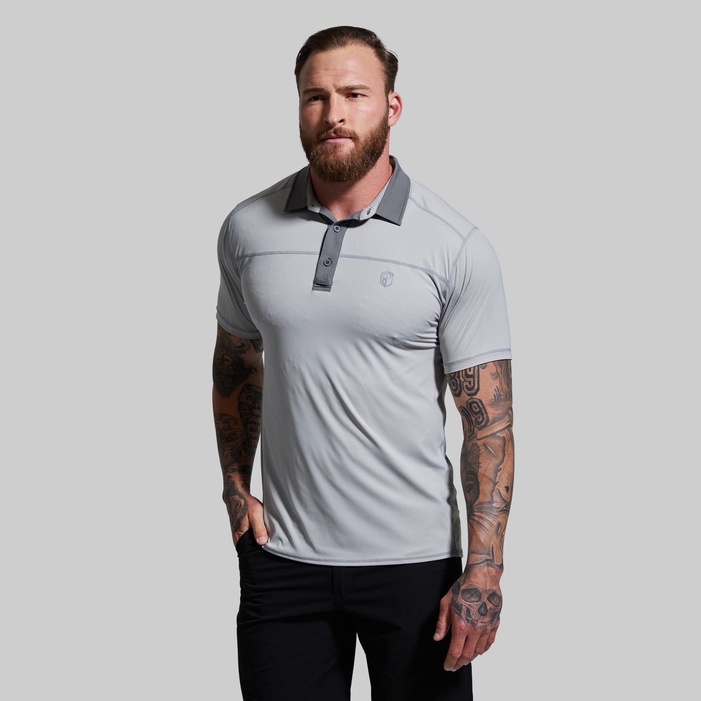 Man wearing a light gray polo shirt with a collar on a plain background