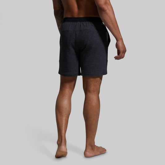 Person wearing dark gray shorts on a plain background