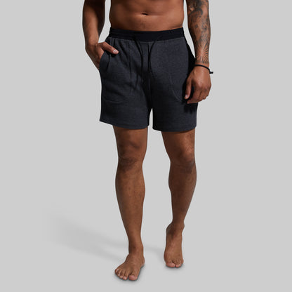 Man wearing dark gray shorts on a gray background