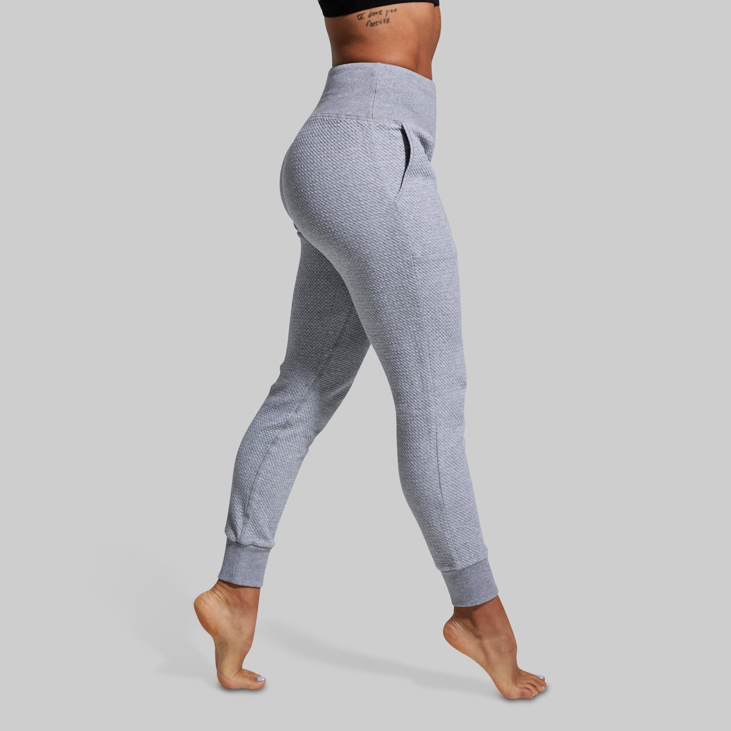 Person wearing gray joggers on a plain background