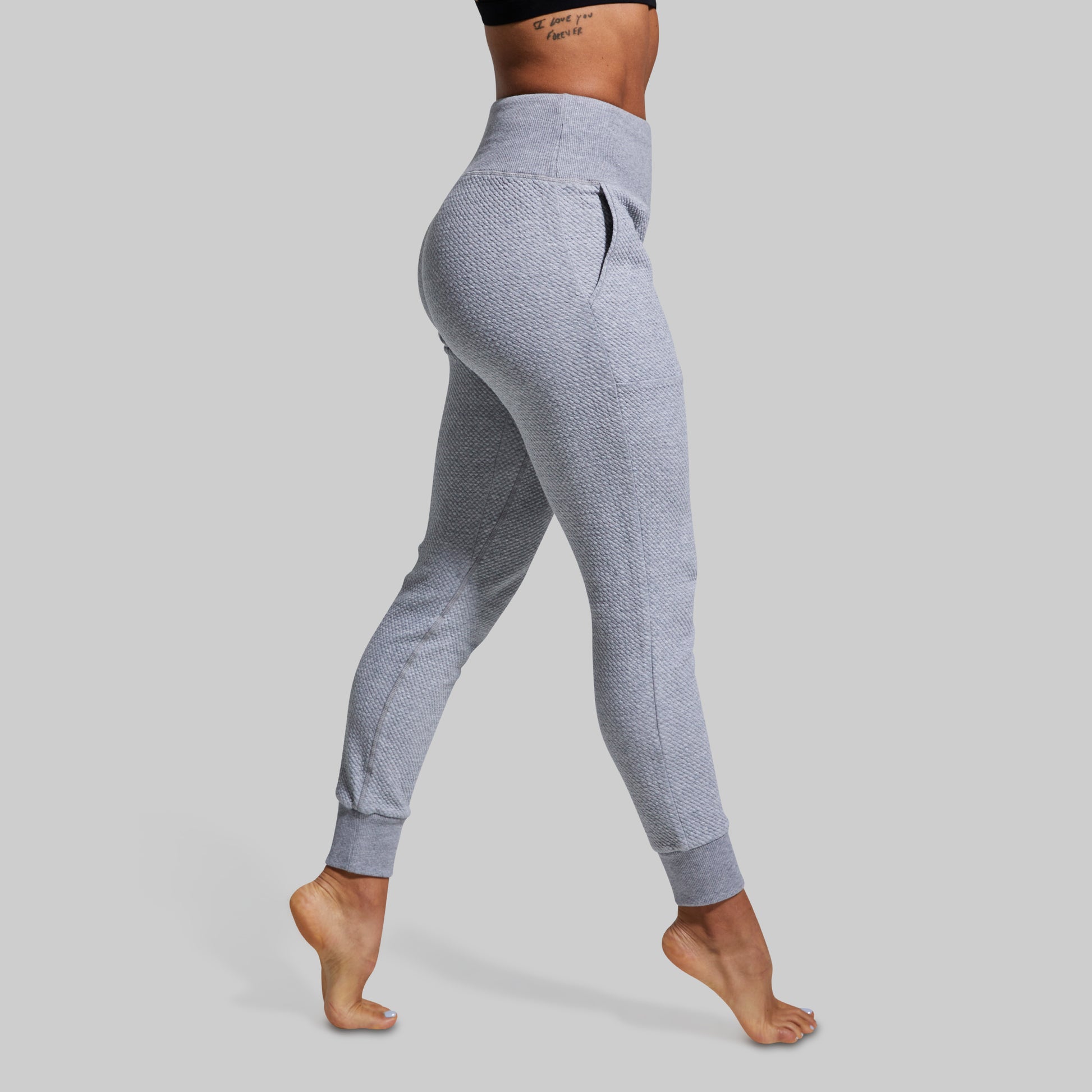 Person wearing gray joggers on a plain background