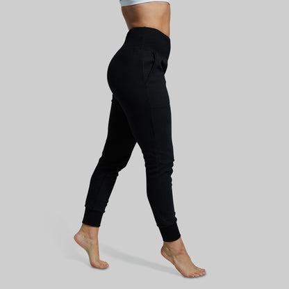 Black jogger pants worn by a person on a gray background