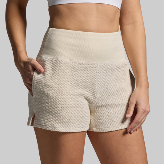 Beige shorts worn by a person on a plain background