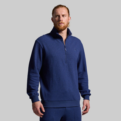Man wearing a blue pullover against a gray background