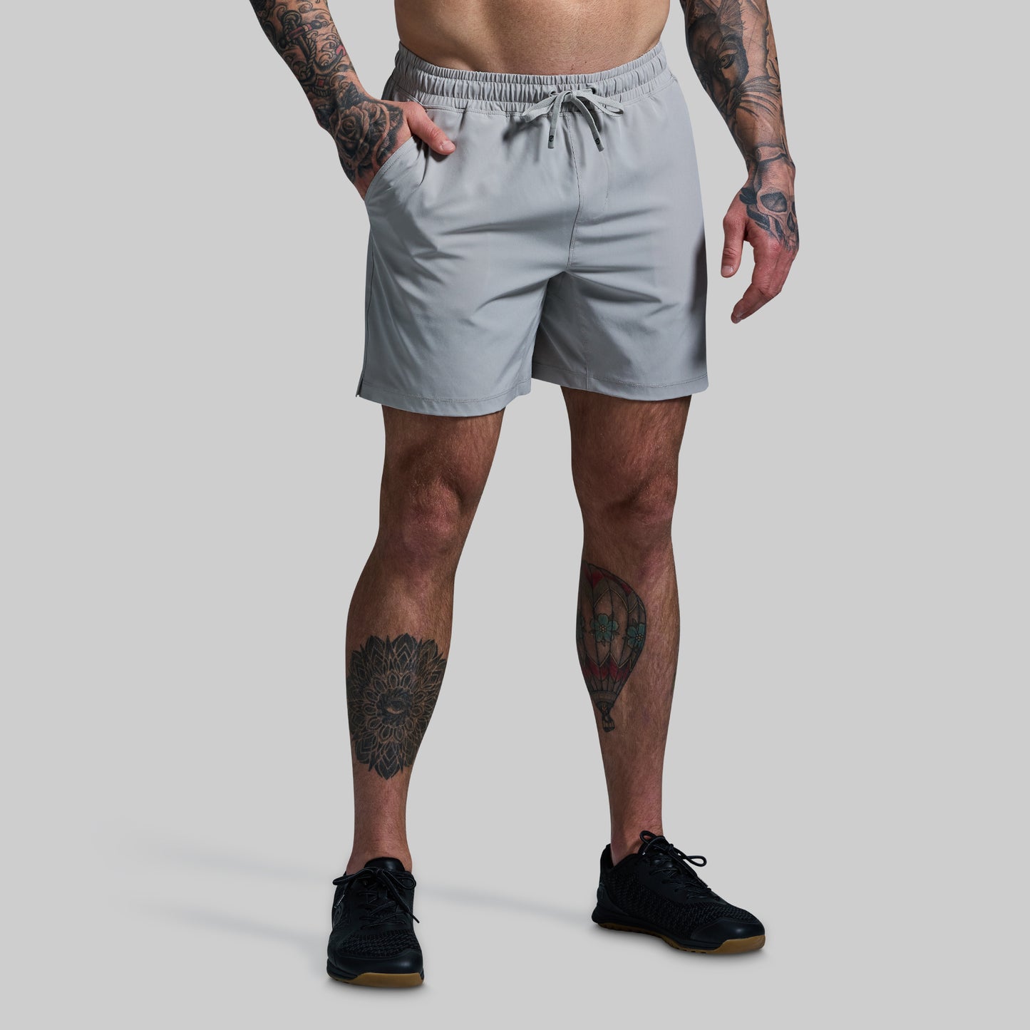 Person wearing light gray shorts on a plain background
