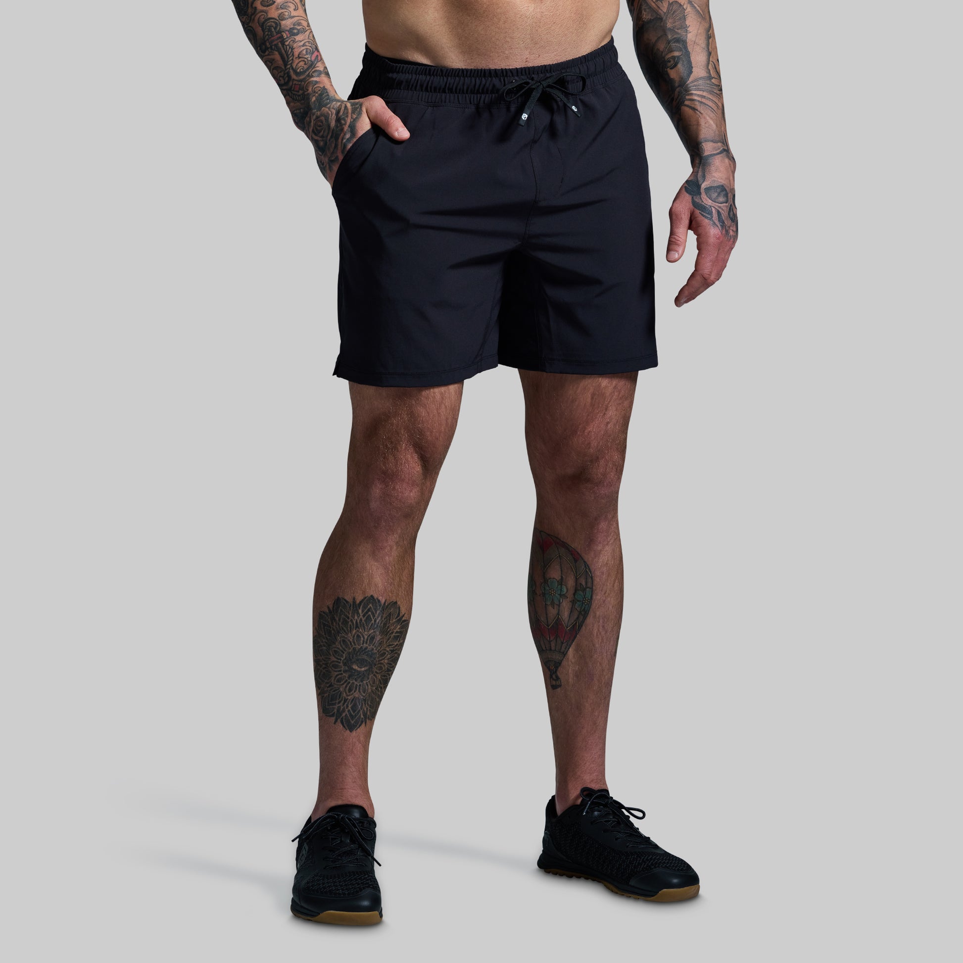 Person wearing black shorts on a gray background
