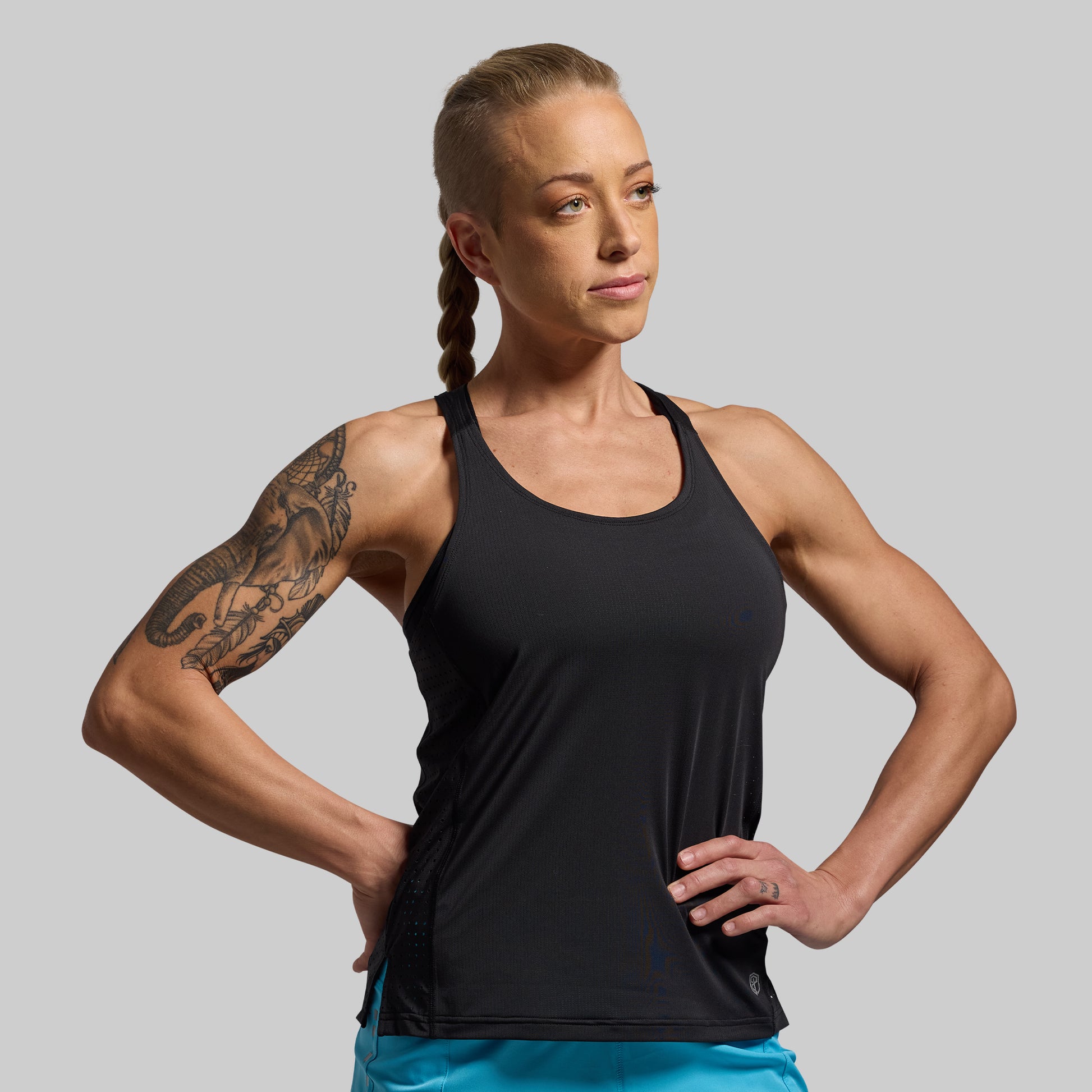 Woman wearing a black tank top against a gray background