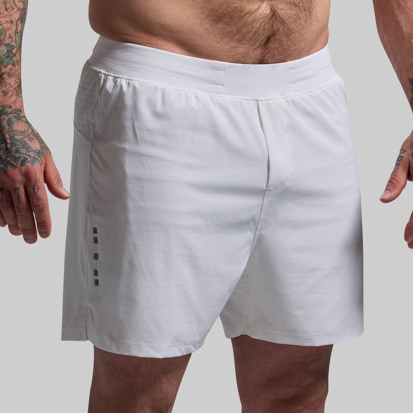 White athletic shorts worn by a person on a plain background