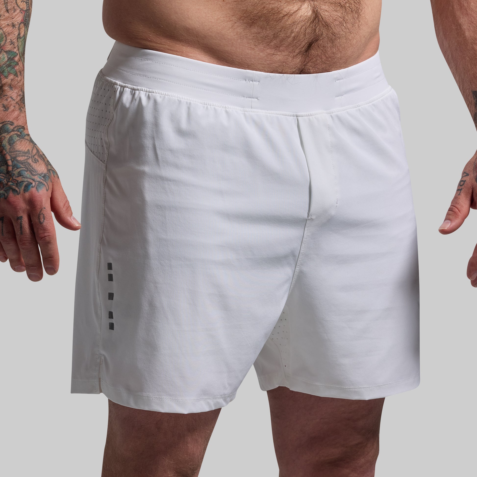 White athletic shorts worn by a person on a plain background