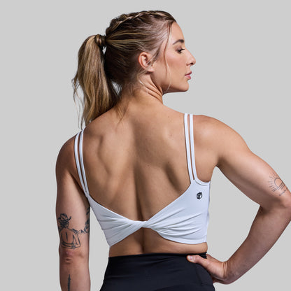 Woman wearing a white sports bra with a gray background