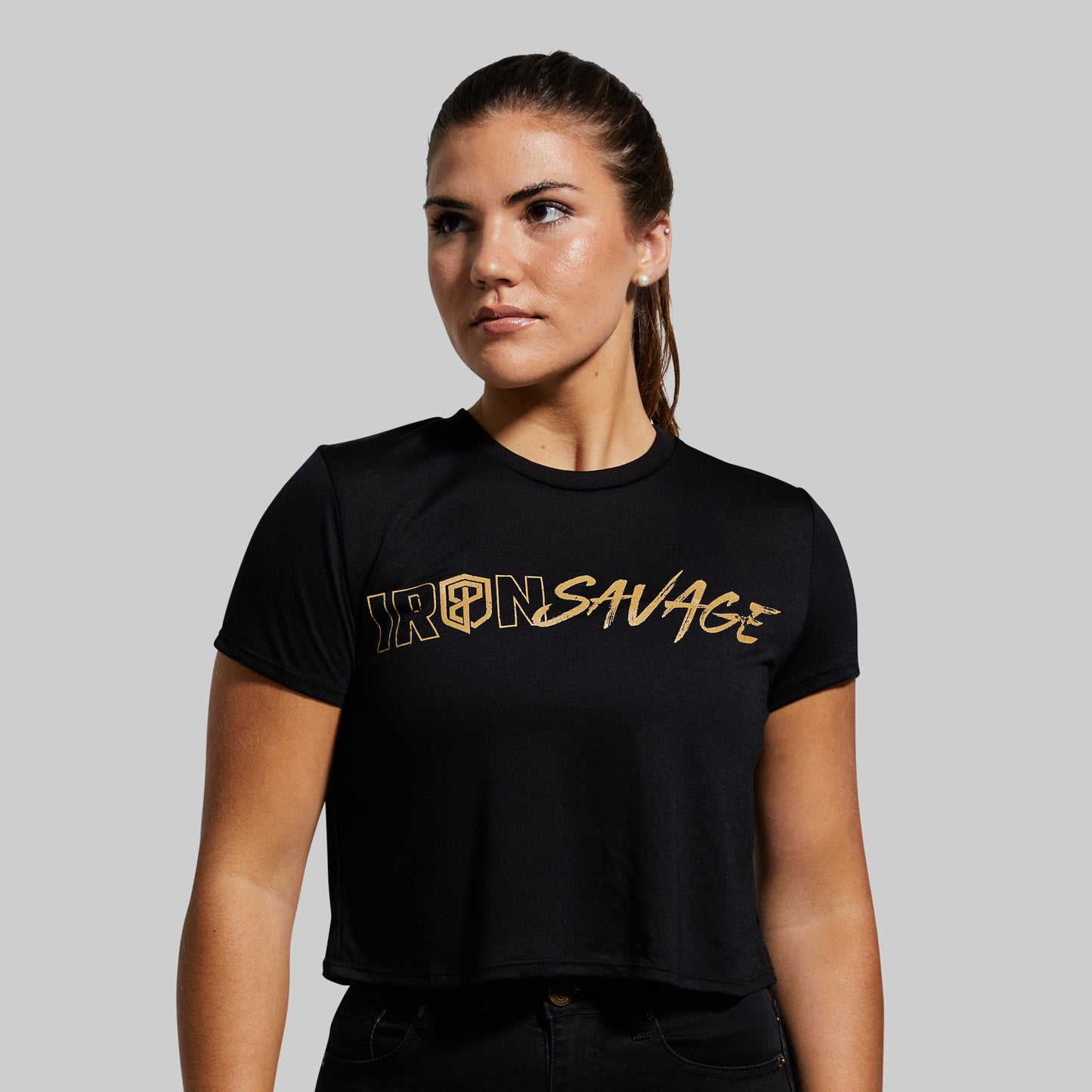 Woman wearing a black t-shirt with 'IRON SAVAGE' printed in gold on a gray background