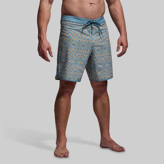 Man wearing blue patterned shorts on a gray background