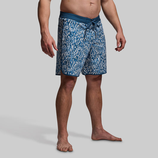 Person wearing blue patterned swim shorts on a gray background