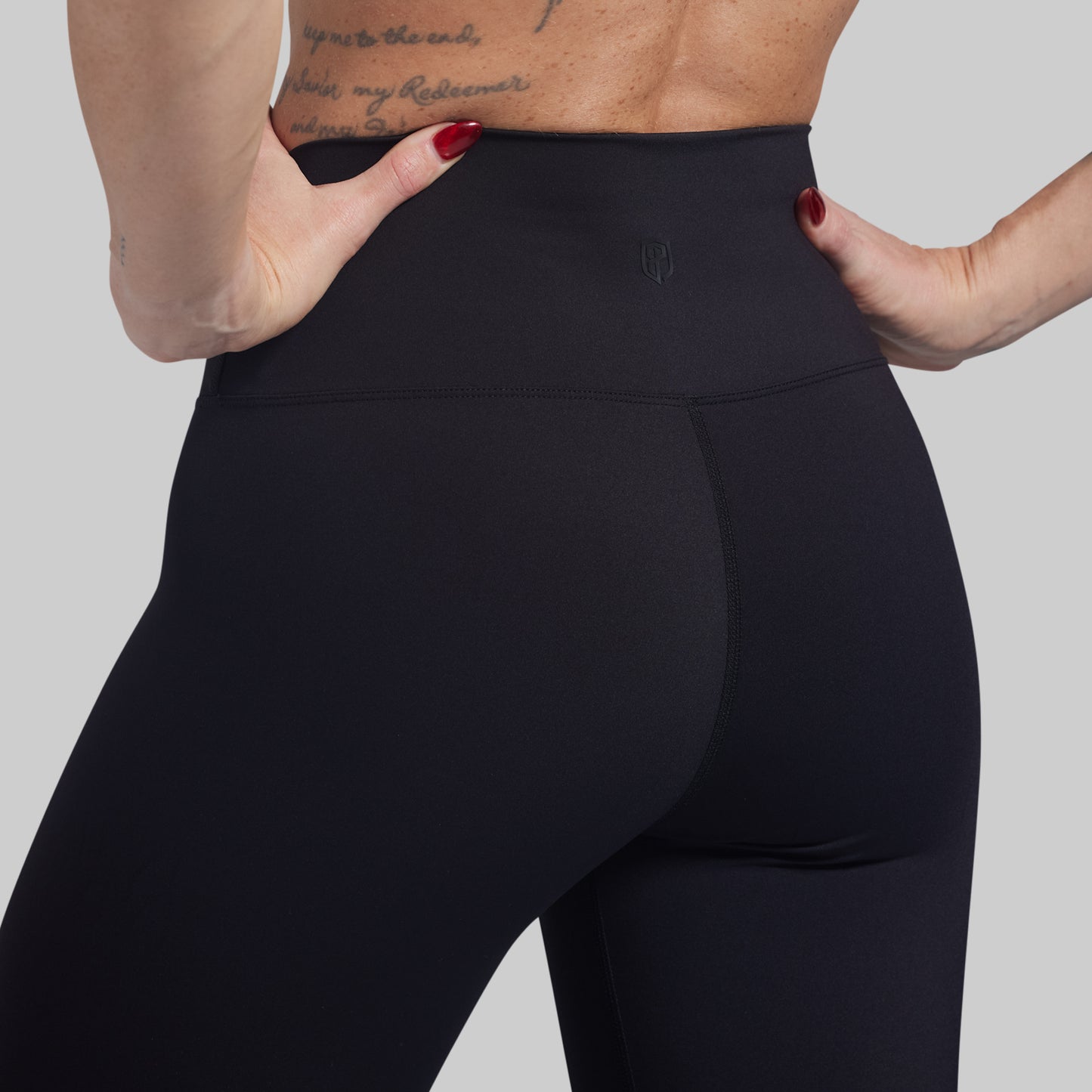 Person wearing black leggings with a plain background