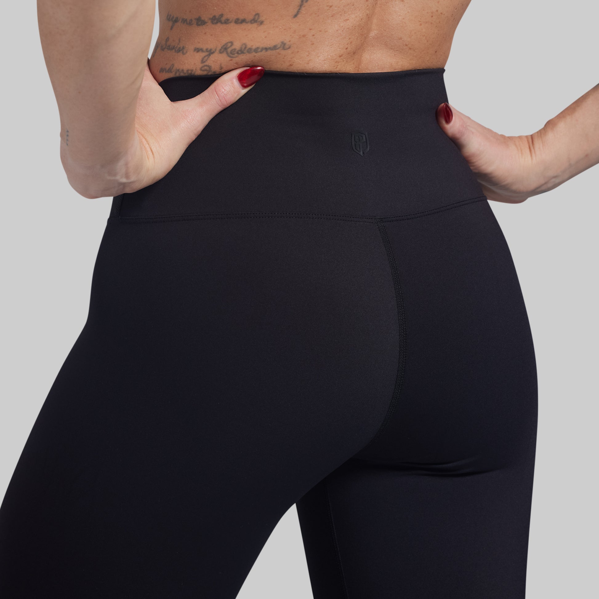 Person wearing black leggings with a plain background